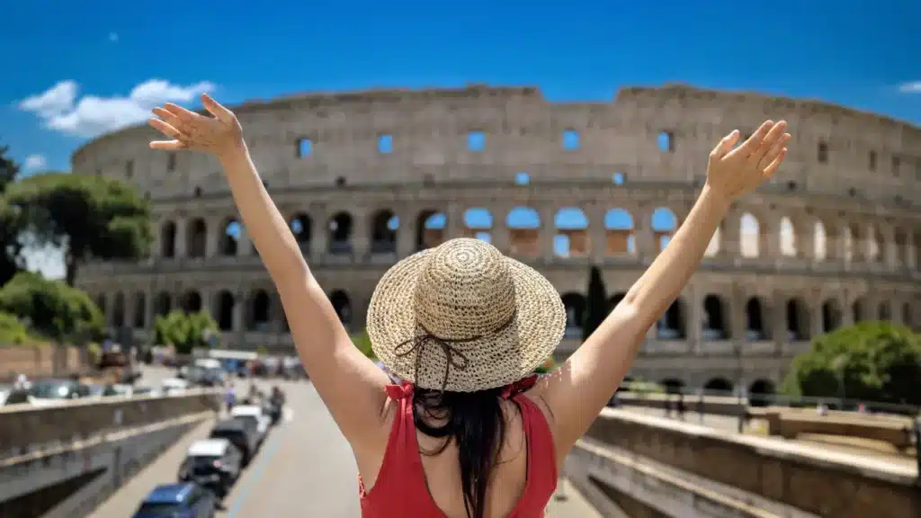 Mulher feliz ao se deparar com o Coliseu em Roma. - Quanto custa viajar para a Itália em 2026.