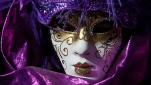 Close em uma luxuosa máscara de Carnaval veneziano nas cores roxo e dourado, com detalhes brilhantes e penas, representando a elegância das festividades italianas.